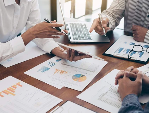 Close-up of business professionals in Madison, WI, analyzing financial charts and spreadsheets on a laptop for ROI optimization and profit maximization.