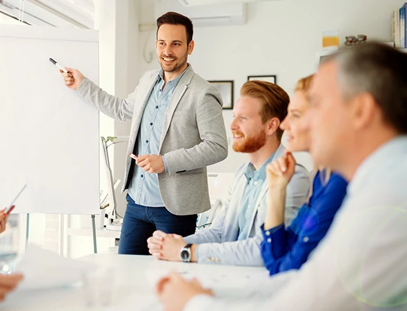 A professional business growth coach in a grey blazer giving a whiteboard presentation to a team to improve revenue and operational efficiency.