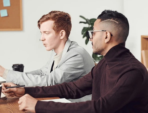Two male colleagues focused on a discussion at a desk, representing professional decision-making guidance services in Columbus, Ohio.