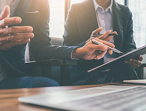 Close-up of professional colleagues in suits reviewing a results-oriented coaching strategy on a tablet in Chicago, Illinois.