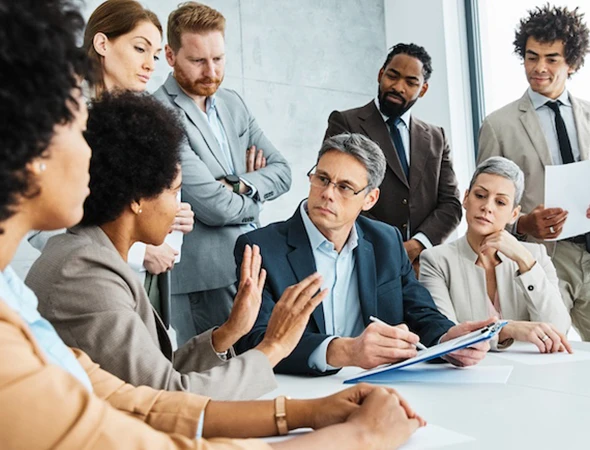 A diverse group of corporate professionals and an executive coach discussing strategic leadership goals around a conference table.